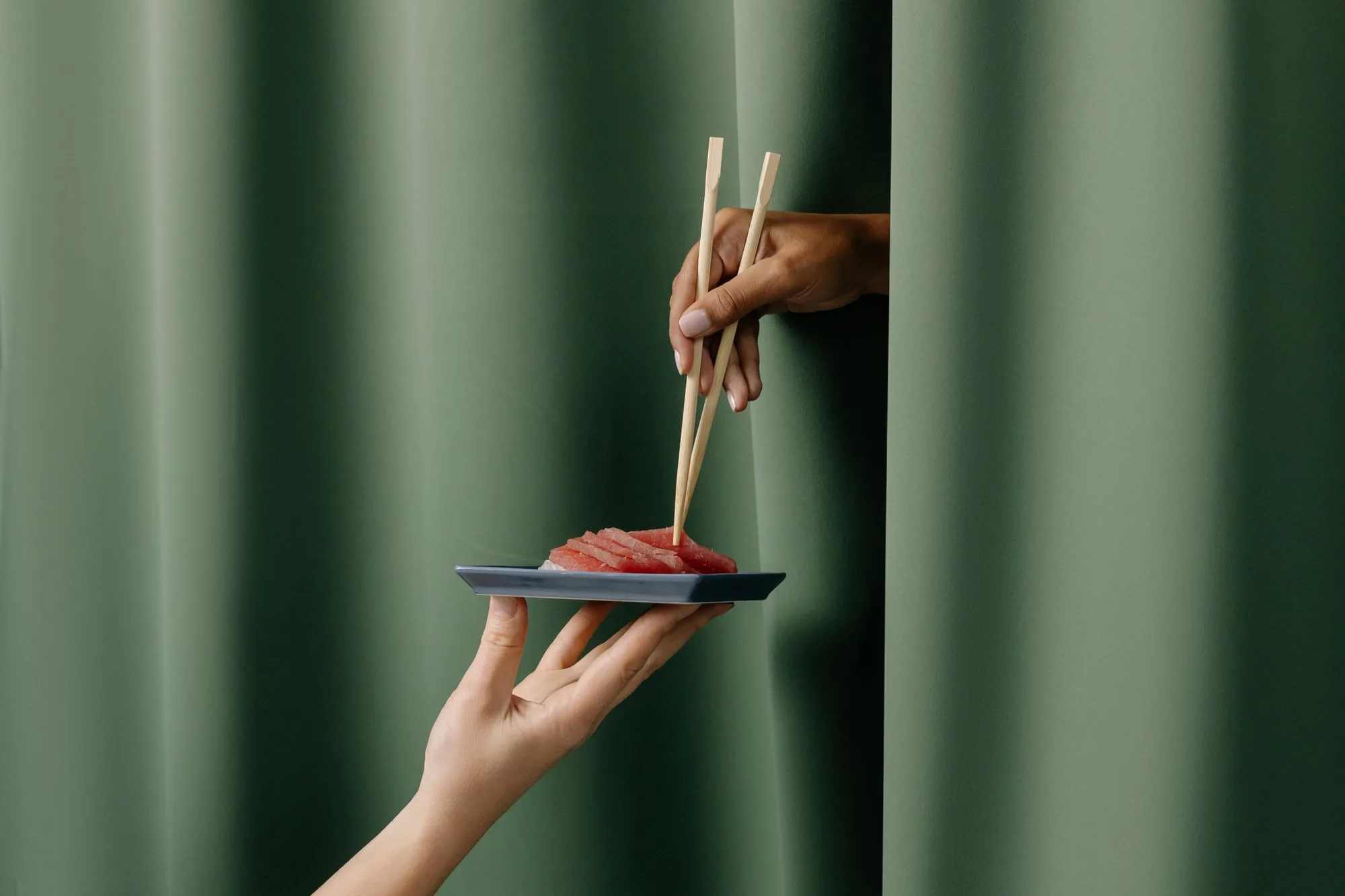Sashimi presented across a deep green dining curtain.