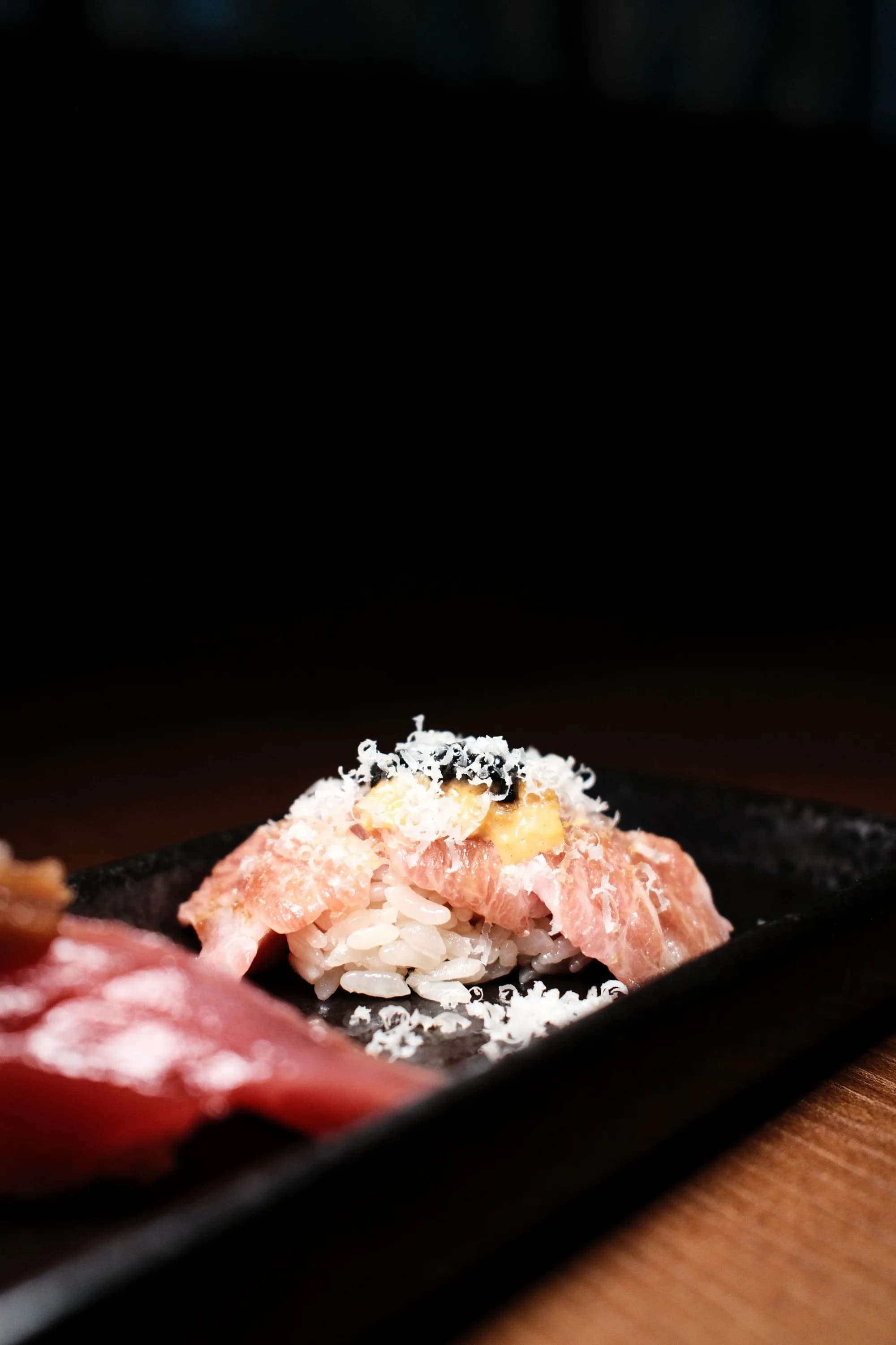 Nigiri finished with a delicate garnish on a dark ceramic plate.