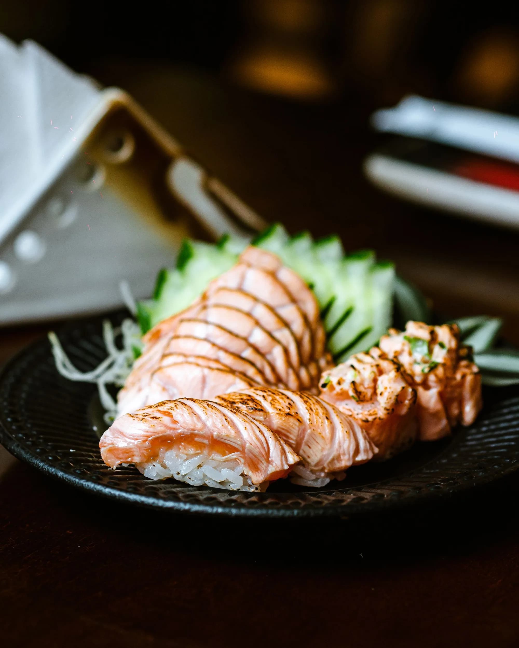 Aburi salmon nigiri arranged on a black plate.
